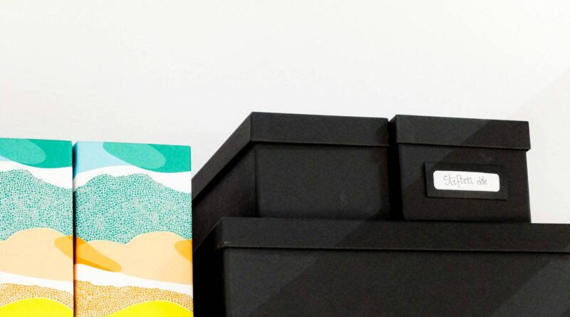 A stack of colorful and black storage boxes neatly arranged on a shelf.